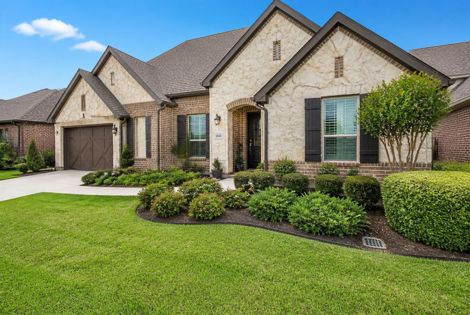 Well-drained Texas home exterior with a landscape drainage inlet near the flower bed